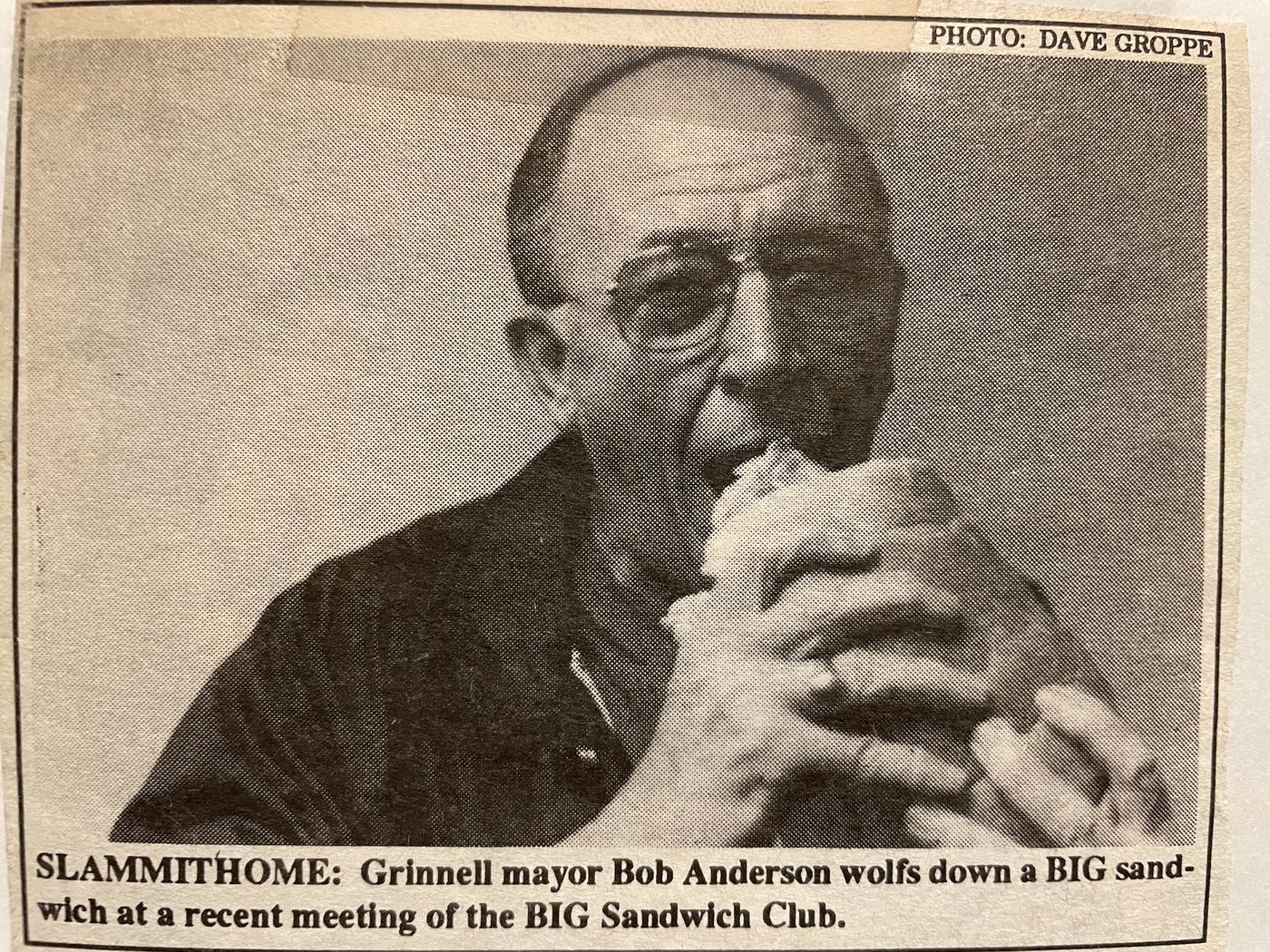 Newspaper clipping: Grinnell mayor Bob Anderson wolfs down a BIG sandwich at a recent meeting of the BIG Sandwich Club. Photo by Dave Groppe.